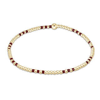 Gold and burgundy beaded bracelet on a white background
