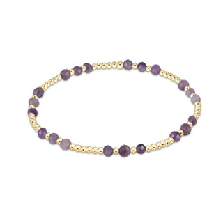 Bracelet with purple beads on a gold band against a white background