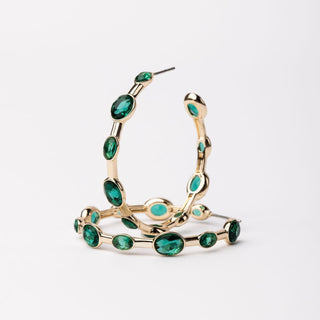 Gold hoop earrings with green gemstones on a white background