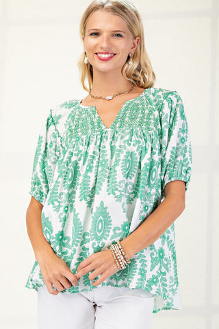 Woman wearing a green and white patterned blouse on a plain background