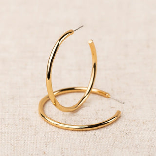 Gold hoop earrings on a beige fabric background