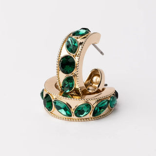 Gold hoop earring with green gemstones on a white background