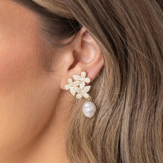Close-up of a woman wearing a gold earring with pearl drop.