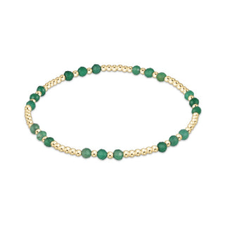 Gold bracelet with green beads on a white background
