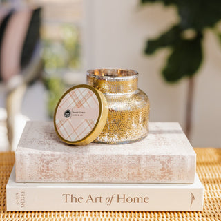 Decorative jar with gold accents on top of books titled 'The Art of Home' on a table.