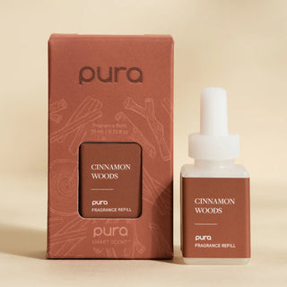 Pura Cinnamon Woods fragrance refill bottle and packaging on a beige background