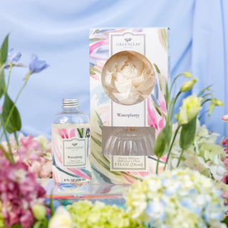 Greenleaf diffuser and packaging surrounded by flowers on a blue background