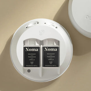 Noma fragrance refills in a round white container on a beige background
