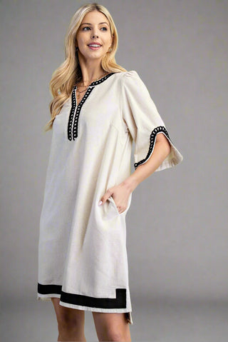 Woman wearing a white dress with black trim on a gray background