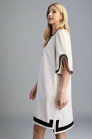 Woman wearing a white dress with black accents on a gray background