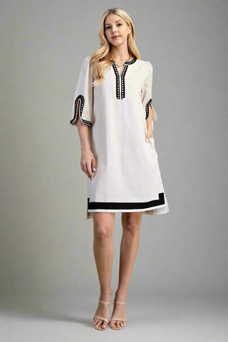 Woman wearing a white dress with black accents on a gray background