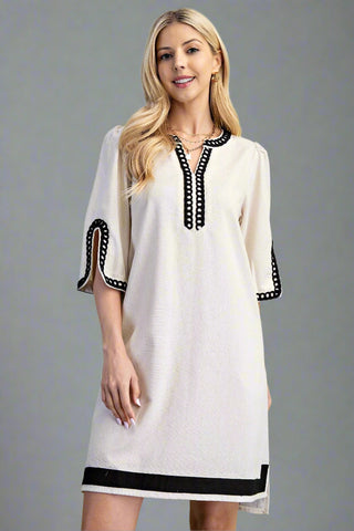 Woman wearing a white dress with black accents on a gray background