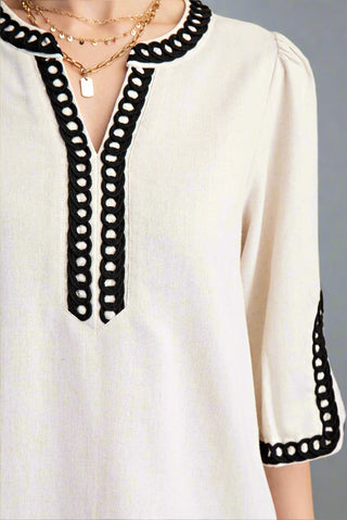 White blouse with black lace trim on a gray background