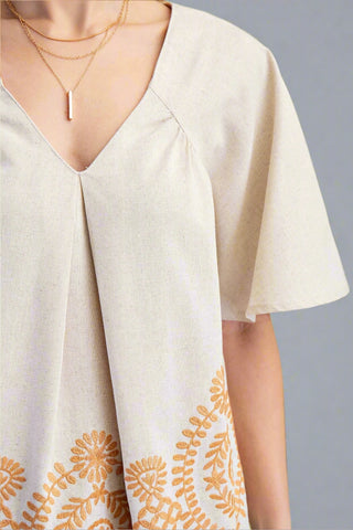 Beige blouse with floral patterns on a plain background