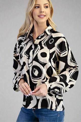 Woman wearing a black and white patterned blouse against a gray background