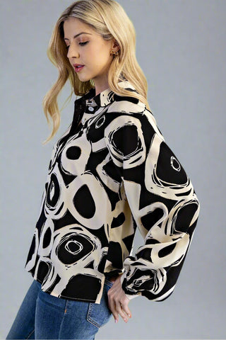 Woman wearing a black and white patterned blouse against a gray background