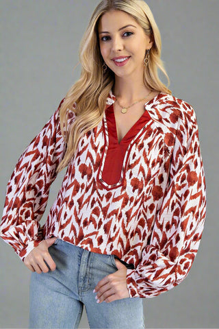 Woman wearing a red and white patterned blouse with blue jeans on a gray background