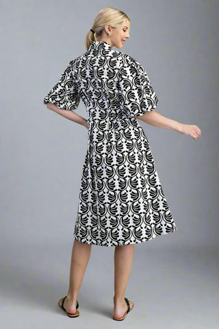 Woman wearing a black and white patterned dress on a gray background