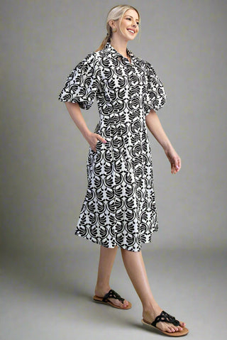 Woman wearing a black and white patterned dress on a gray background