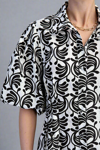 Black and white patterned dress worn by a person on a green background
