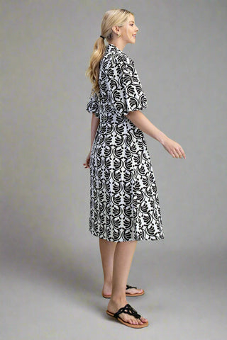 Woman wearing a black and white patterned dress on a gray background