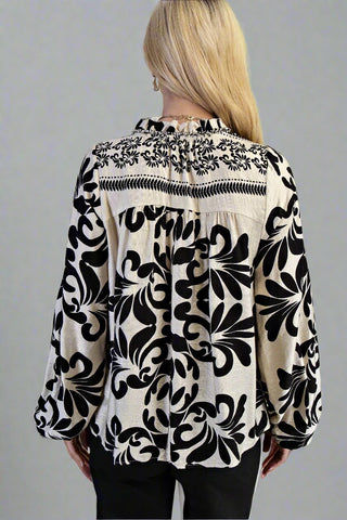 Woman wearing a black and white patterned blouse against a gray background