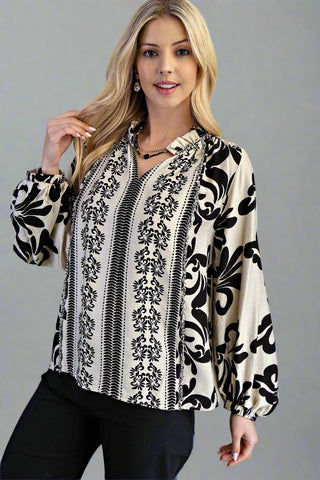 Woman wearing a black and white patterned blouse against a gray background