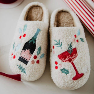 Pair of white slippers with festive designs on a light background