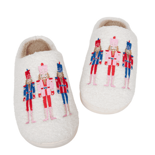 Pair of white slippers with embroidered nutcracker design on a white background