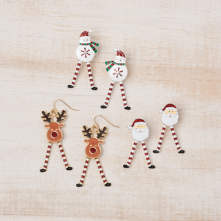 Set of Christmas-themed earrings including Santa, reindeer, and snowman on a light wood background.